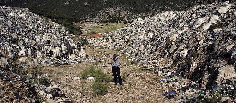 Reporter Eurydice Bersi walks among the piles of waste that remain around the now closed Maratholaka landfill in Greece's southern Peloponnese.