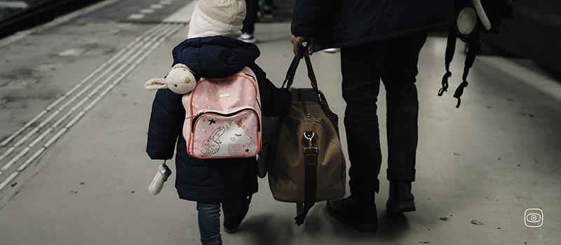 A child walking on a train platform with a guardian. 