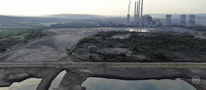 a field with some industrial plants in the background