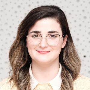 Dallandyshe Xhaferri, journalist. A young woman wearing glasses, somewhat smiling into the camera