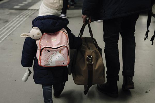 A child walking on a train platform with a guardian. 