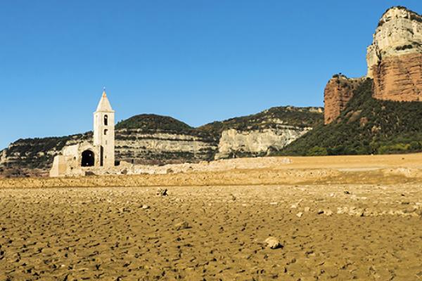 Sau Reservoir in Catalonia, now empty. Dry landscape, blue skies