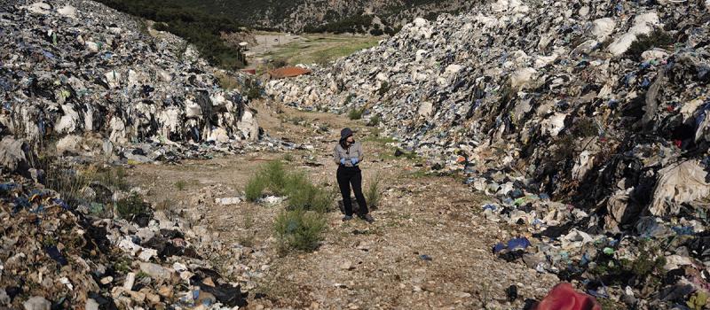 Reporter Eurydice Bersi walks among the piles of waste that remain around the now closed Maratholaka landfill in Greece's southern Peloponnese.