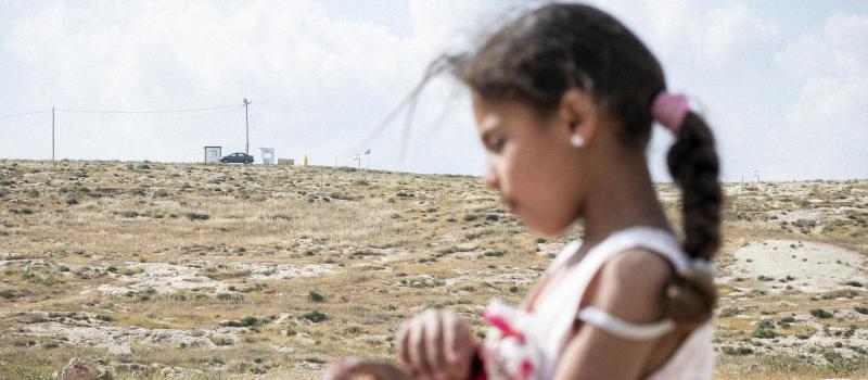 Het zesjarige meisje dat woont in een van de dorpen van Masafer Yatta staat voor de heuvel die leidt naar een Israelische outpost. 